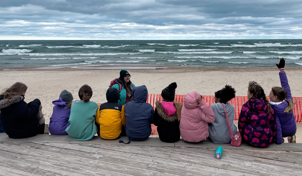 Kids learning from their teacher on a Lake Michigan beach